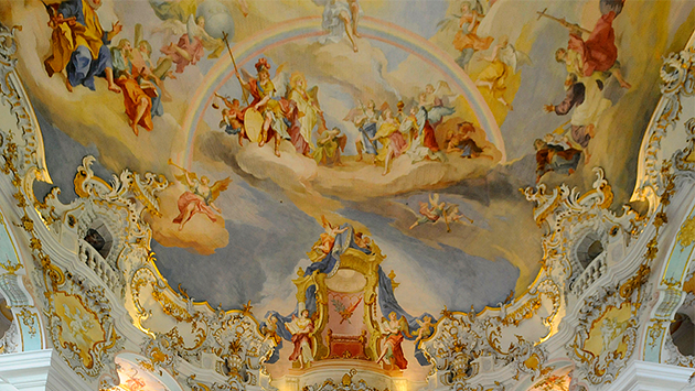 Cropped image of a German Baroque altar with a ceiling fresco of angels, clouds, and a rainbow.